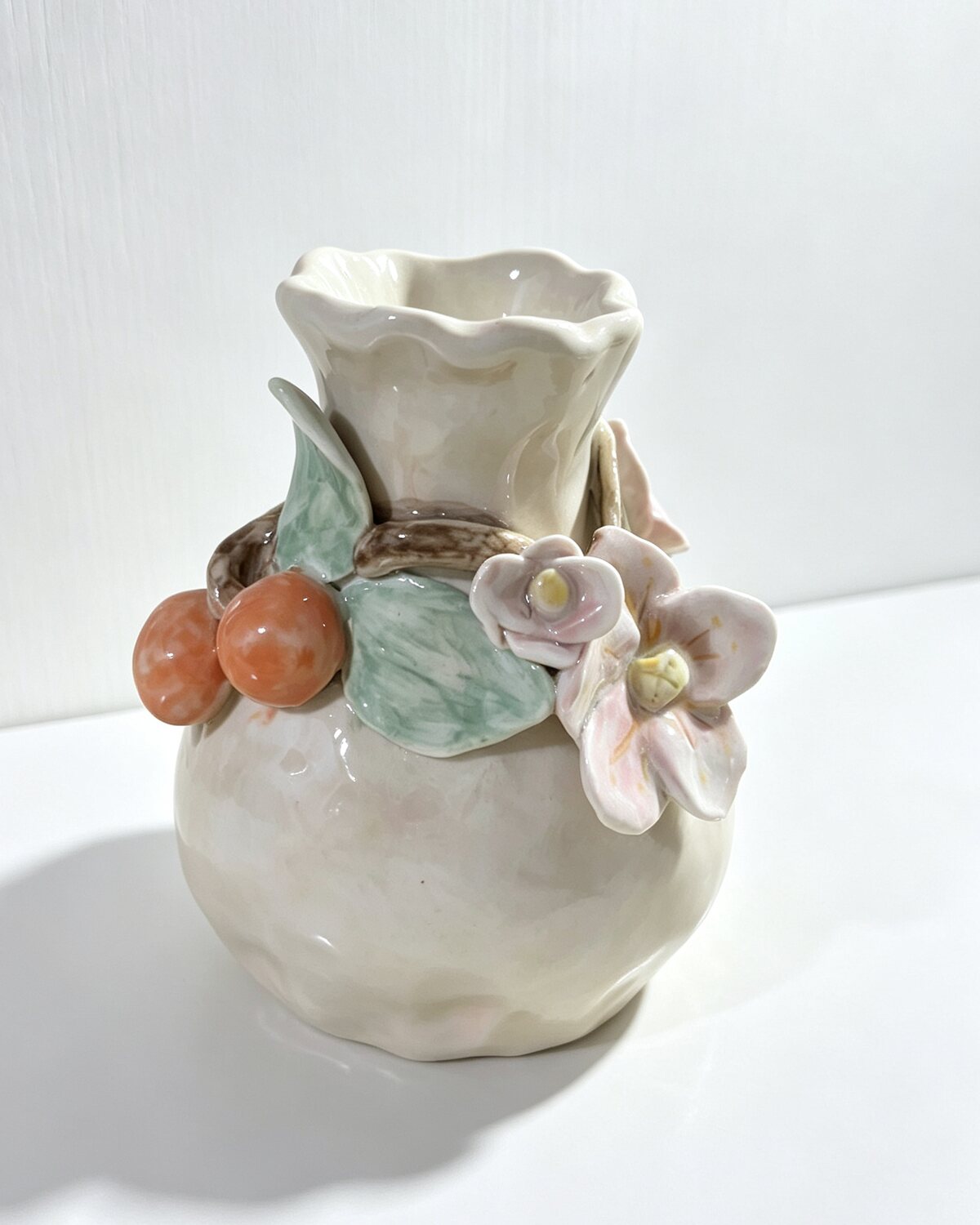 Cream-glazed vase with hand-built fruit, flowers, and leaves